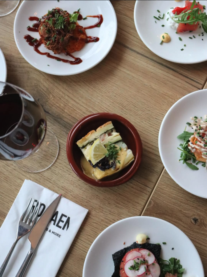 Tafel met verschillende tapasgerechtjes en een glas rode wijn bij Rodaen in Bunnik